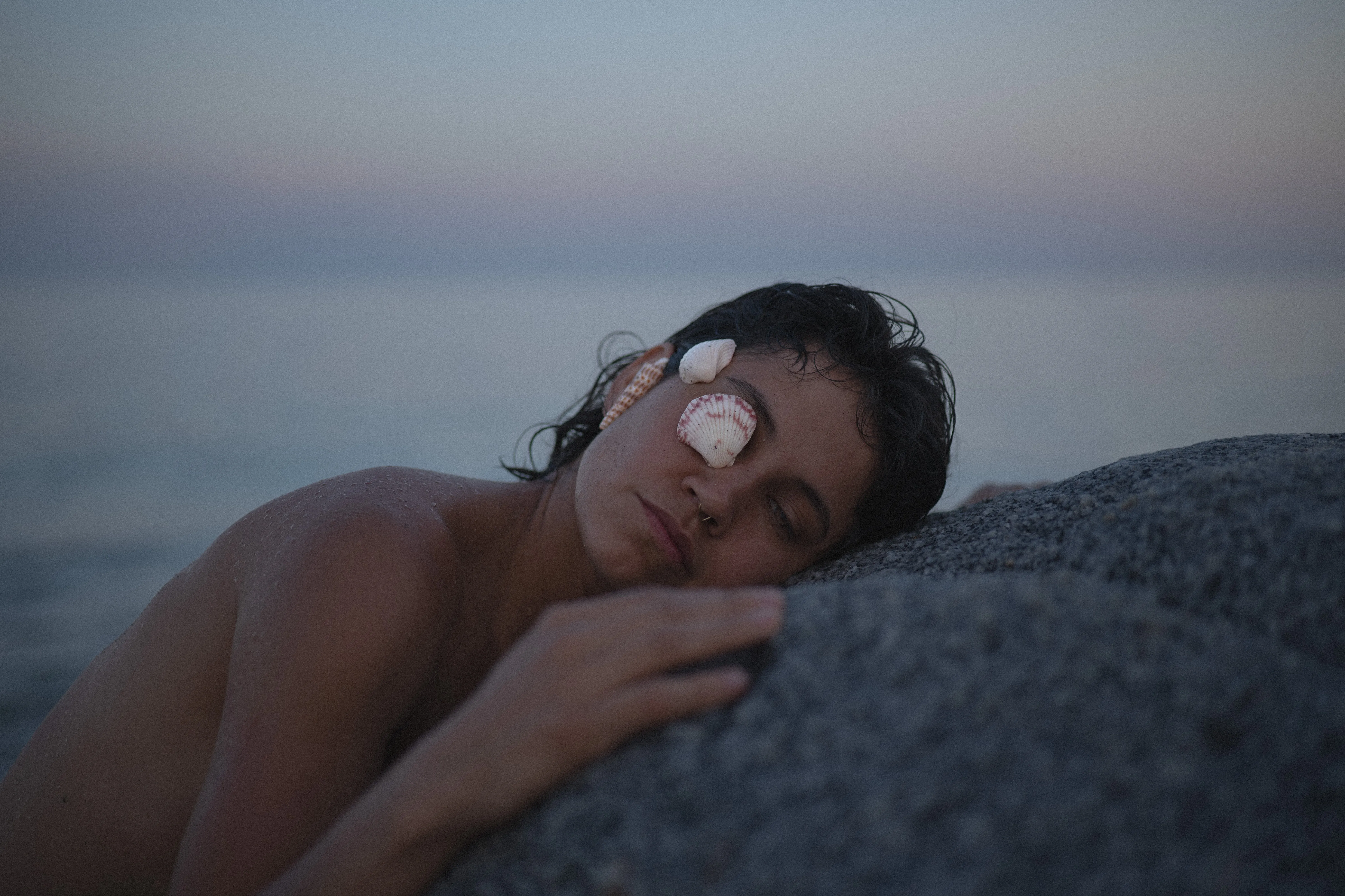 girl resting her head on a rock with shells on her face, playa la gaviota near los barriles, la paz, baja california sur, at blue hour