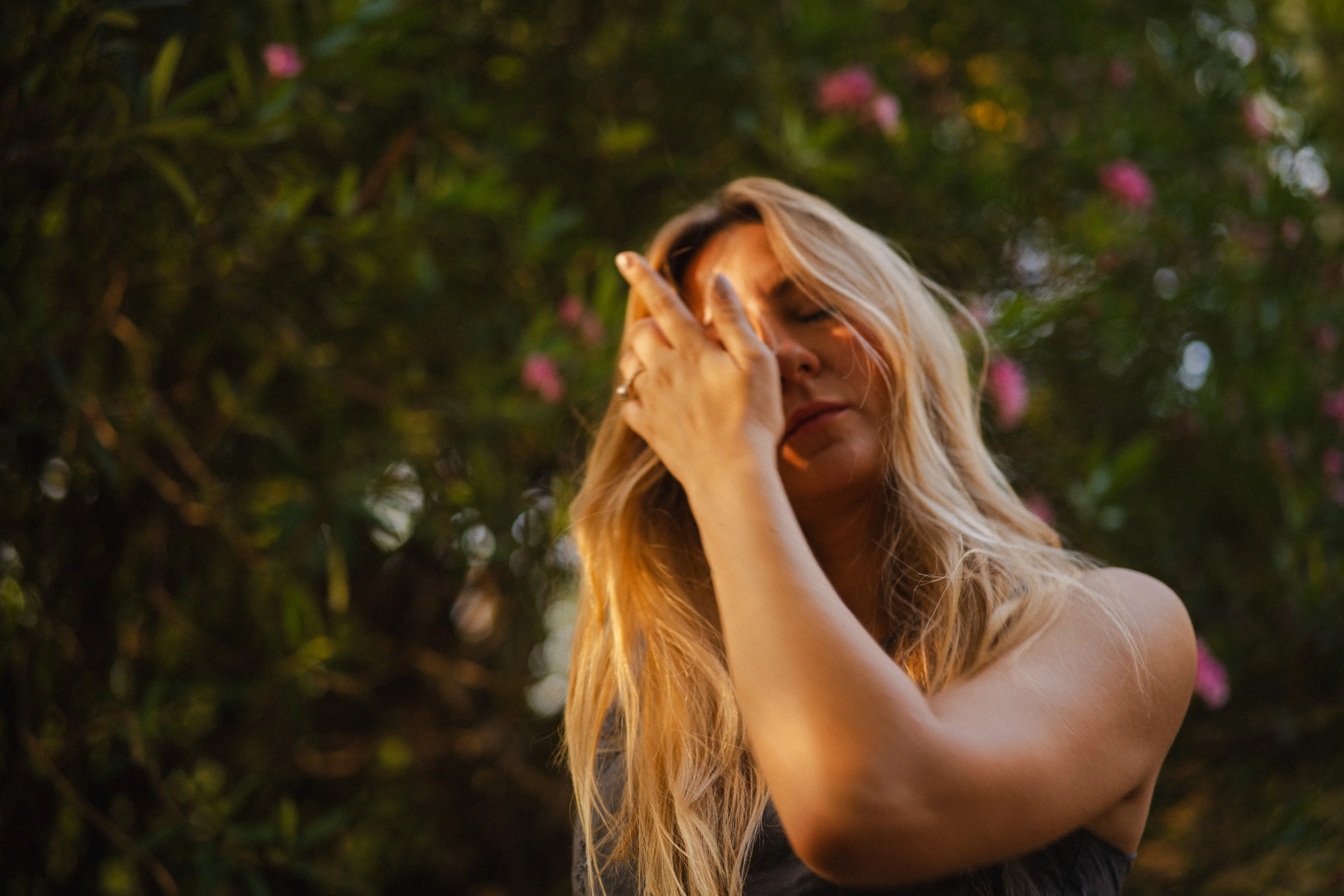 portrait of an italian woman with long blonde hair in le colombare park, verona, italy, at golden hour: eyes closed in the sun, under the leaves, on a park bench