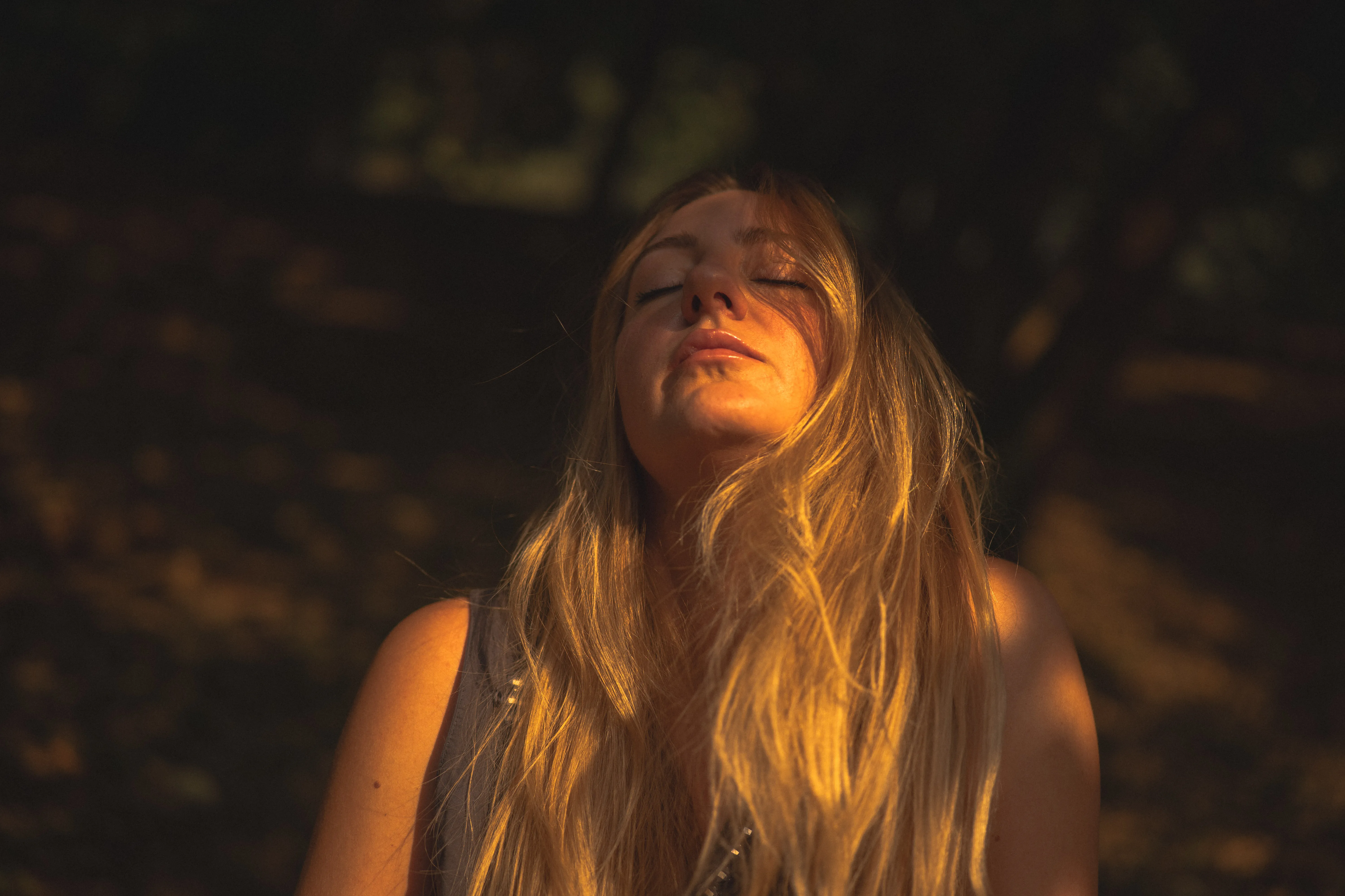 portrait of an italian woman with long blonde hair in le colombare park, verona, italy, at golden hour: eyes closed in the sun, under the leaves, on a park bench (4)
