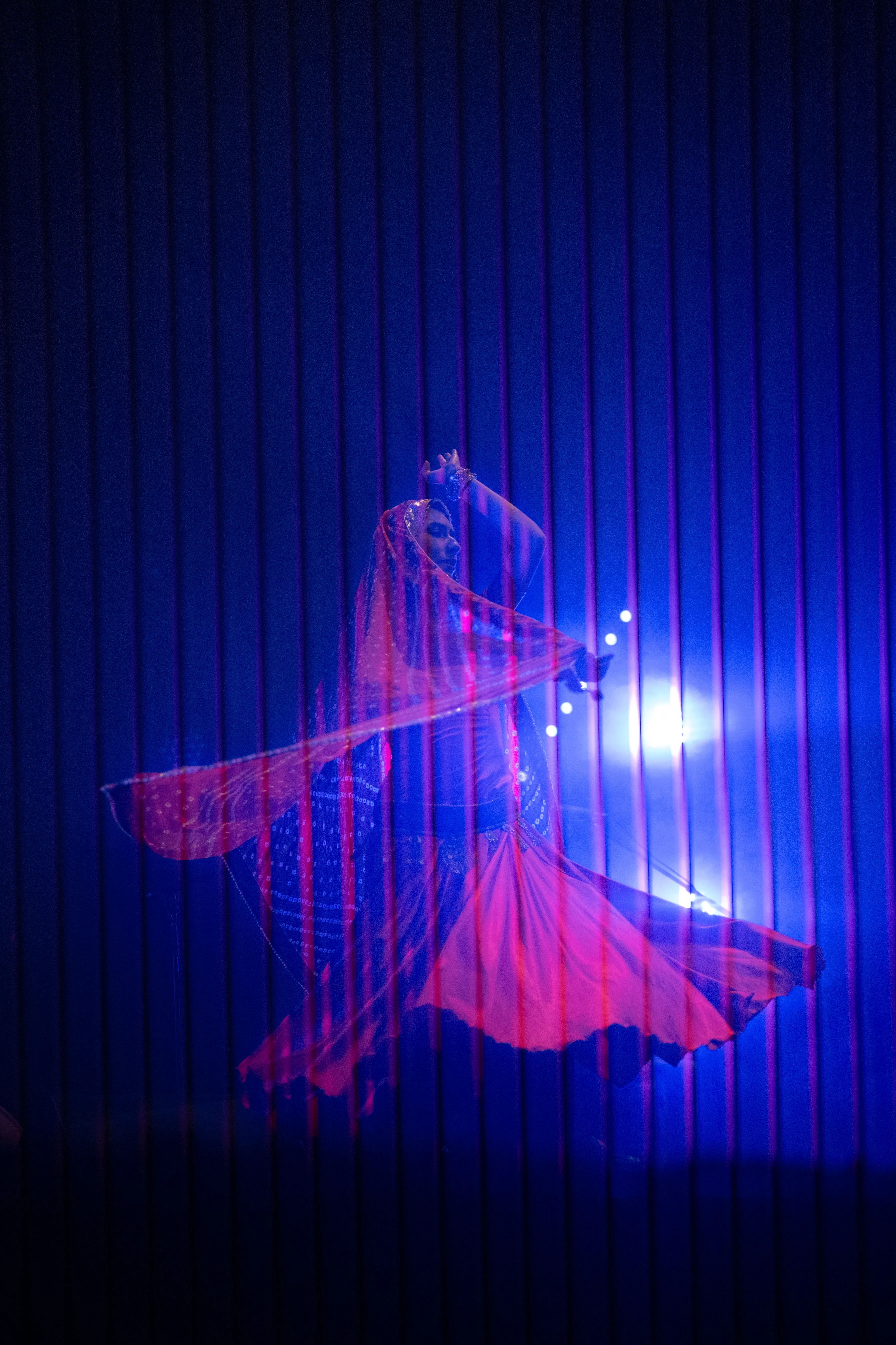claudia llanos, rajasthani dancer from mexico, in a red dress under blue light and smoke, mexico city (cdmx)